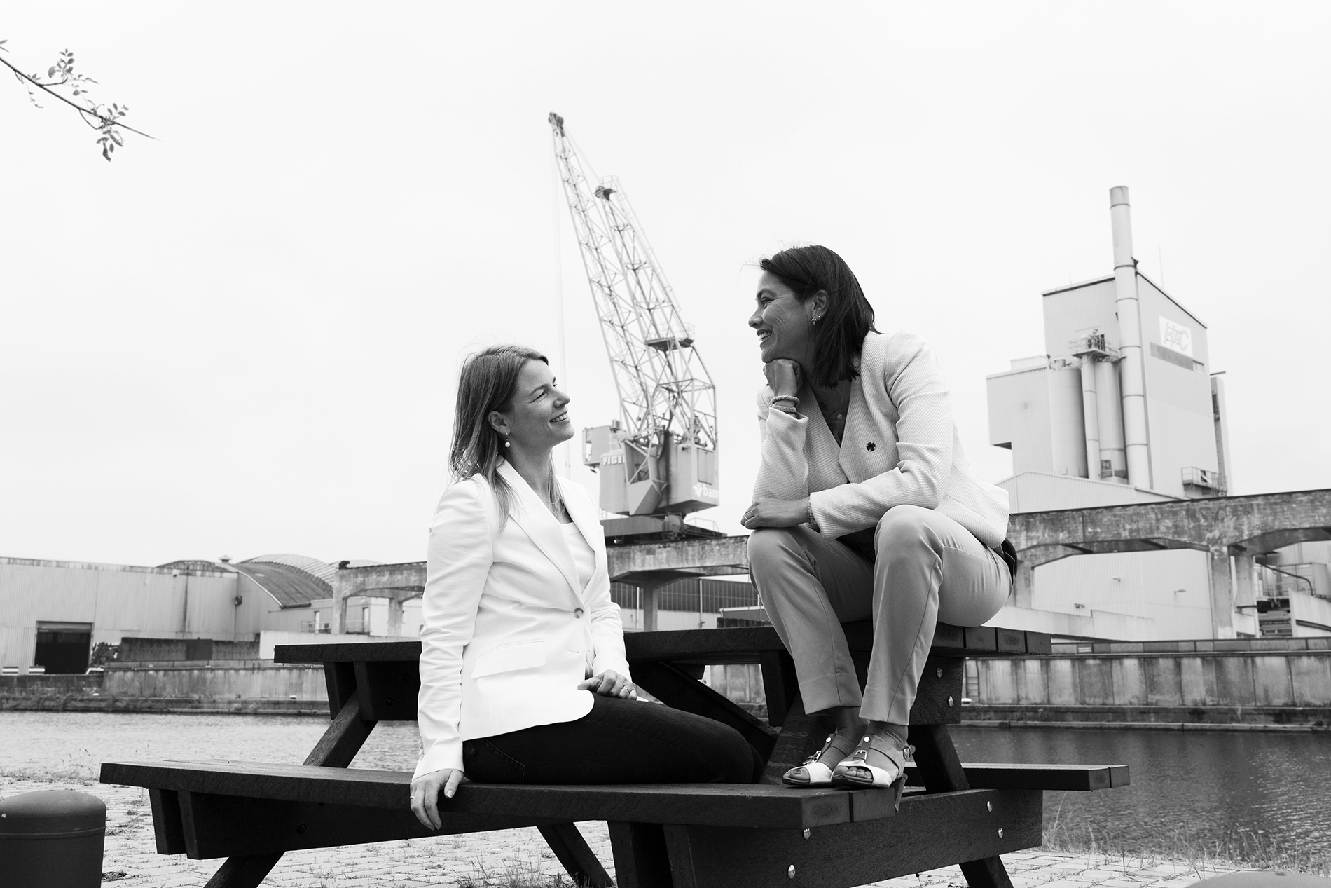 Daphne Laan en Sonja Wekema aan een boardroomtafel, zwart-witfoto